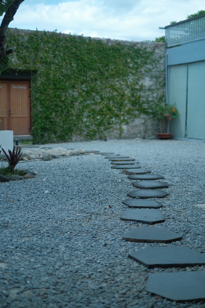 Serene outdoor path with stepping stones on gravel surrounded by lush greenery.